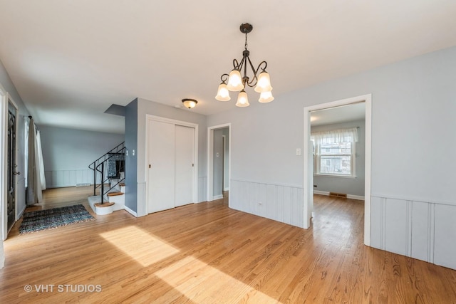 unfurnished room featuring wood-type flooring and an inviting chandelier