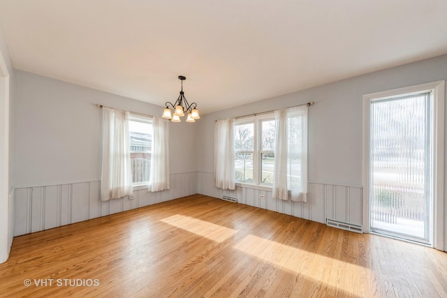 empty room featuring light wood-type flooring and an inviting chandelier