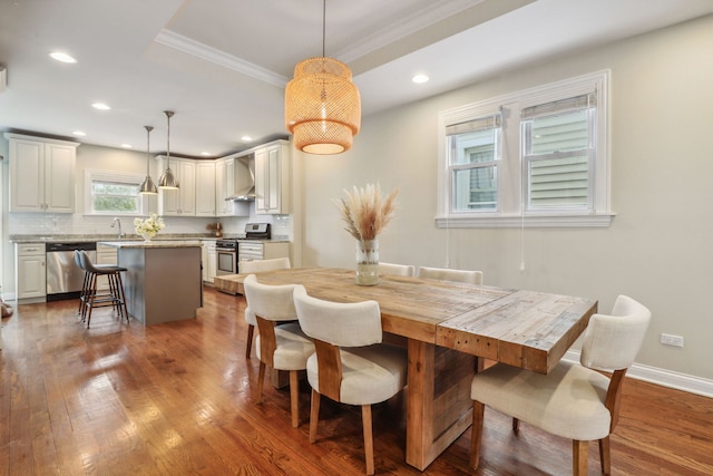 dining area with sink, ornamental molding, and hardwood / wood-style flooring