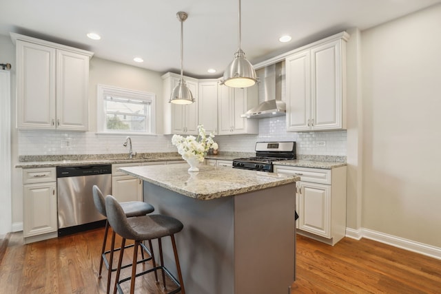 kitchen featuring stainless steel appliances, dark wood-type flooring, wall chimney range hood, white cabinets, and a center island