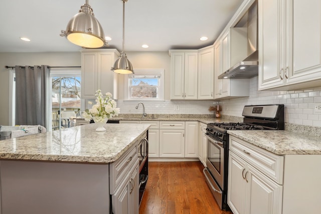 kitchen with wall chimney exhaust hood, white cabinetry, stainless steel appliances, and decorative light fixtures