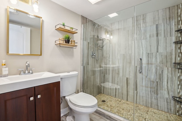 bathroom featuring vanity, toilet, and a shower with door