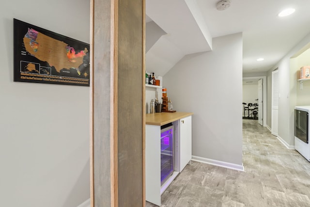 bar featuring wine cooler, light hardwood / wood-style floors, and vaulted ceiling