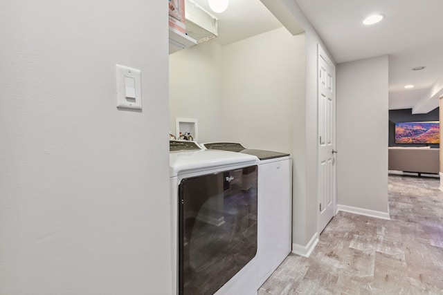 laundry area with separate washer and dryer and light hardwood / wood-style floors