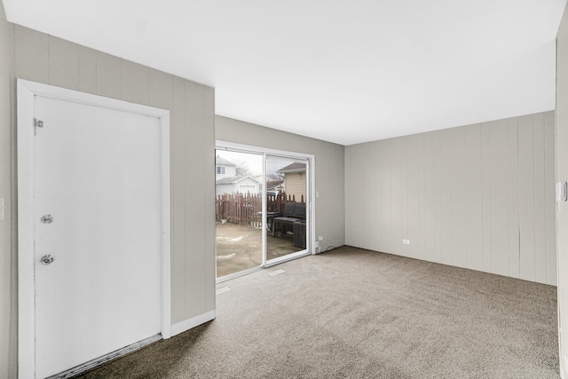 carpeted spare room featuring wood walls