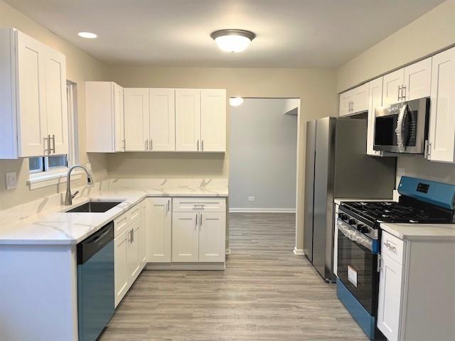 kitchen with white cabinetry, sink, stainless steel appliances, and light hardwood / wood-style floors