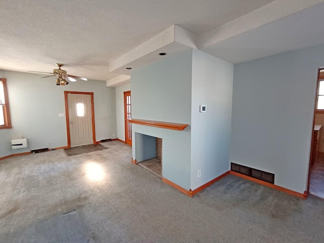 unfurnished living room featuring a textured ceiling, heating unit, plenty of natural light, and ceiling fan