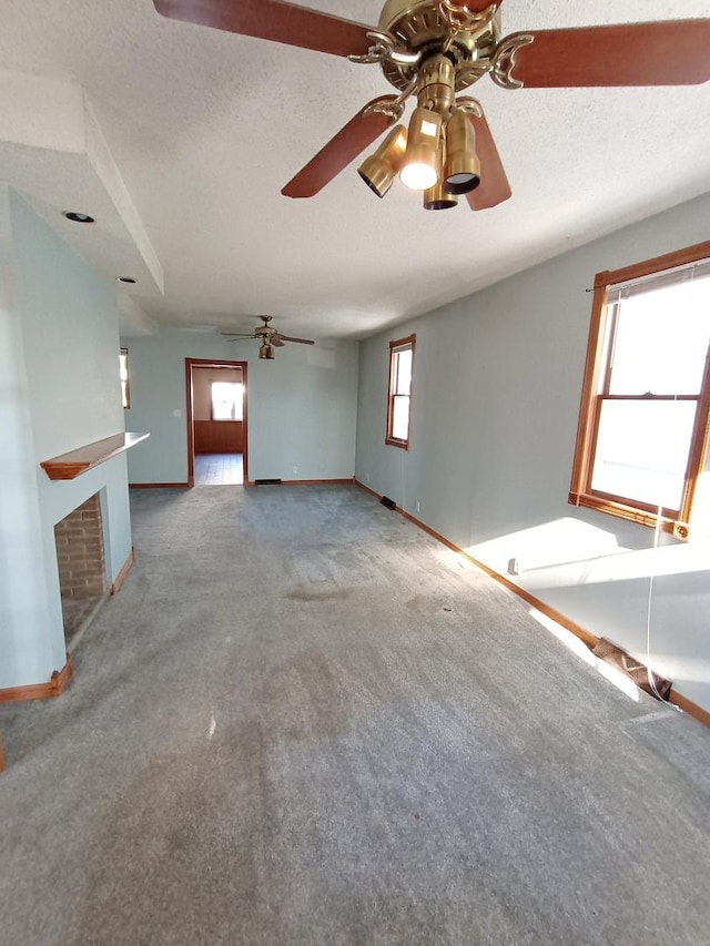 unfurnished living room featuring plenty of natural light, carpet floors, and a textured ceiling