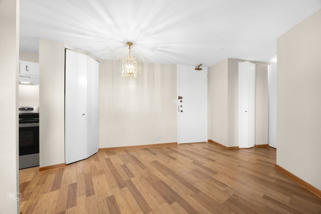 spare room with light hardwood / wood-style floors and a chandelier