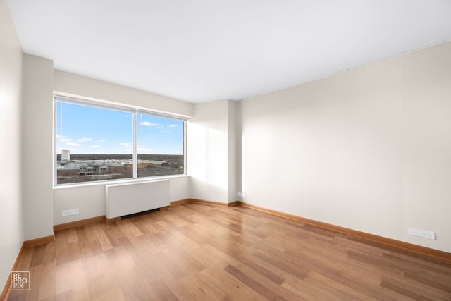 empty room with light wood-type flooring and radiator