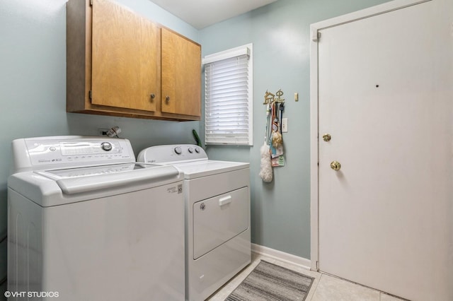 clothes washing area with washer and clothes dryer, light tile patterned flooring, and cabinets