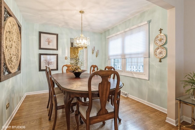 dining space featuring wood-type flooring and a notable chandelier