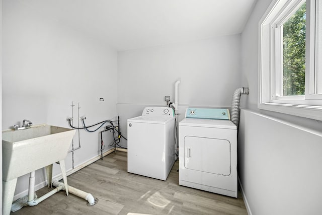 laundry area featuring light hardwood / wood-style floors, washing machine and dryer, and sink