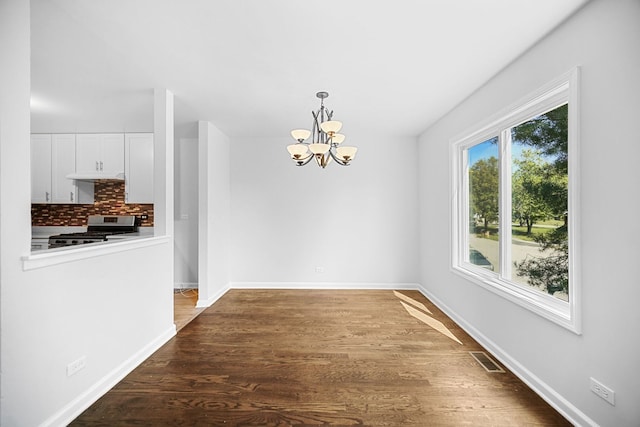 unfurnished dining area with wood-type flooring and an inviting chandelier