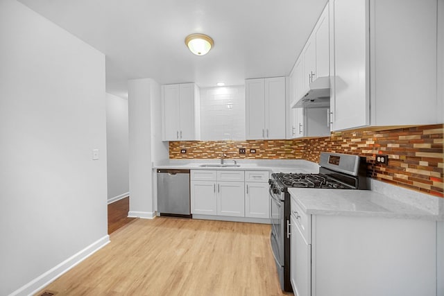 kitchen with sink, light wood-type flooring, appliances with stainless steel finishes, white cabinetry, and extractor fan