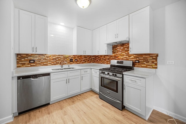 kitchen featuring white cabinets, light wood-type flooring, backsplash, and appliances with stainless steel finishes