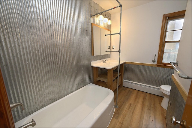 bathroom with vanity, hardwood / wood-style flooring, a baseboard radiator, toilet, and a tub