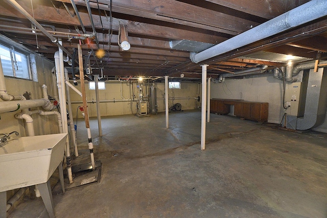 basement featuring a healthy amount of sunlight, sink, and heating unit