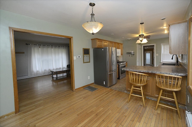 kitchen featuring hardwood / wood-style floors, sink, appliances with stainless steel finishes, kitchen peninsula, and a breakfast bar area