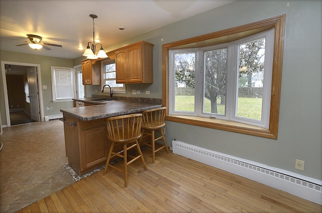 kitchen with decorative light fixtures, a baseboard radiator, plenty of natural light, and sink