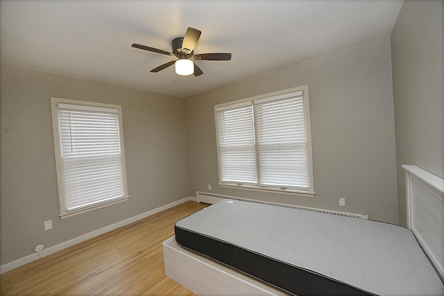 bedroom featuring ceiling fan, light hardwood / wood-style flooring, and multiple windows