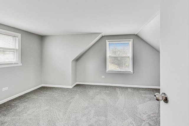 additional living space with carpet floors, a healthy amount of sunlight, and vaulted ceiling