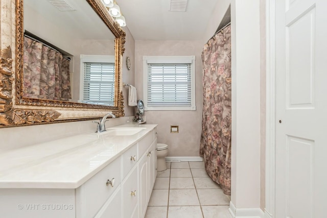 bathroom with toilet, vanity, and tile patterned floors