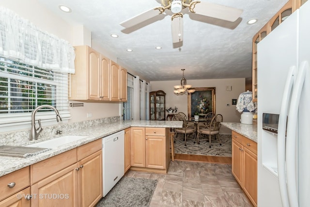 kitchen featuring white appliances, sink, hanging light fixtures, light brown cabinetry, and kitchen peninsula