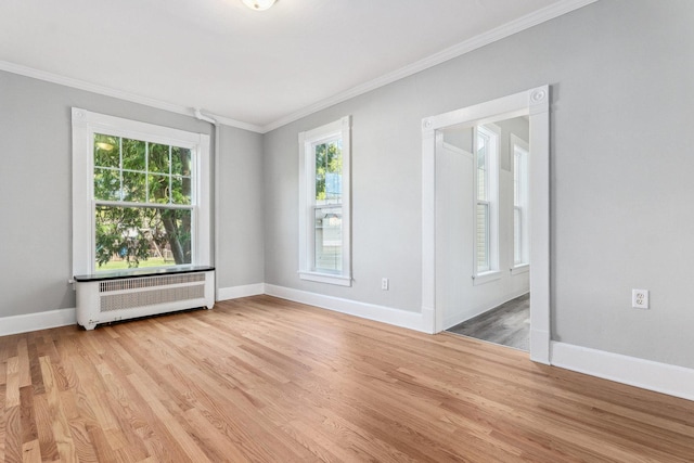 empty room with light hardwood / wood-style floors, radiator heating unit, and crown molding