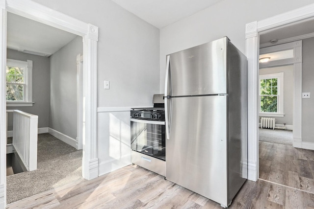 kitchen with radiator heating unit, light hardwood / wood-style flooring, and appliances with stainless steel finishes