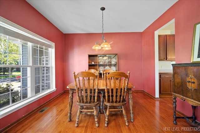 dining space featuring visible vents, wood finished floors, baseboards, and a chandelier