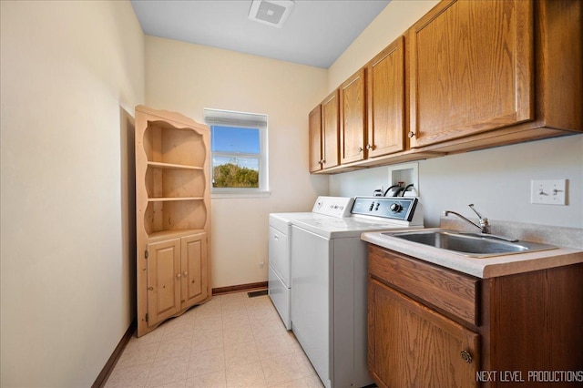 washroom featuring visible vents, a sink, washer and dryer, cabinet space, and baseboards