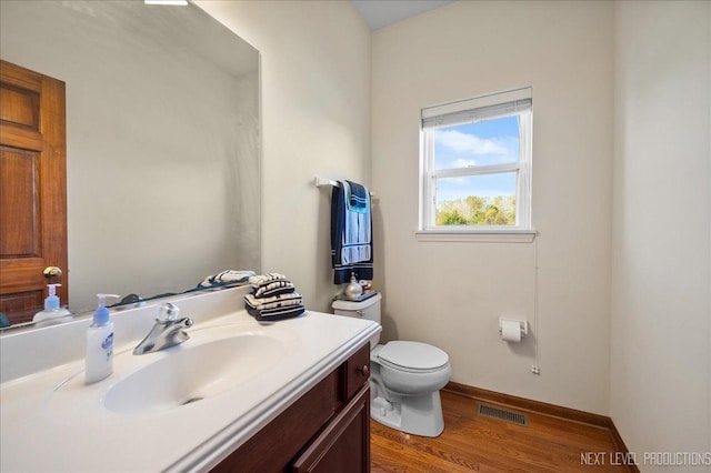 bathroom with visible vents, toilet, wood finished floors, baseboards, and vanity