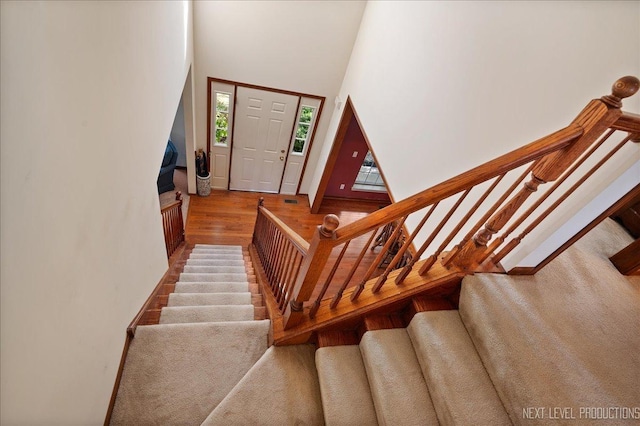 stairway featuring a wealth of natural light, a high ceiling, and wood finished floors