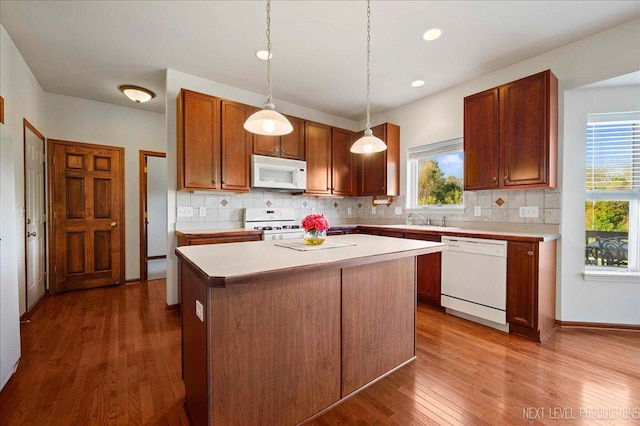 kitchen with dark wood-type flooring, a sink, tasteful backsplash, white appliances, and light countertops