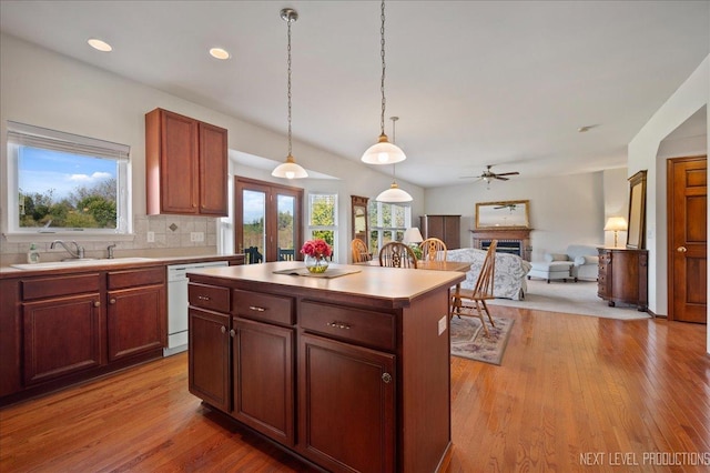 kitchen with backsplash, ceiling fan, light wood-type flooring, white dishwasher, and a sink