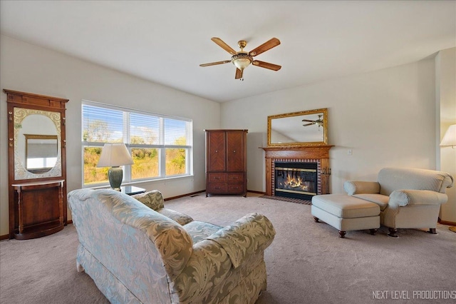 living area with a fireplace, a ceiling fan, baseboards, and carpet floors