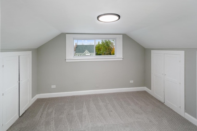 additional living space featuring light colored carpet and vaulted ceiling