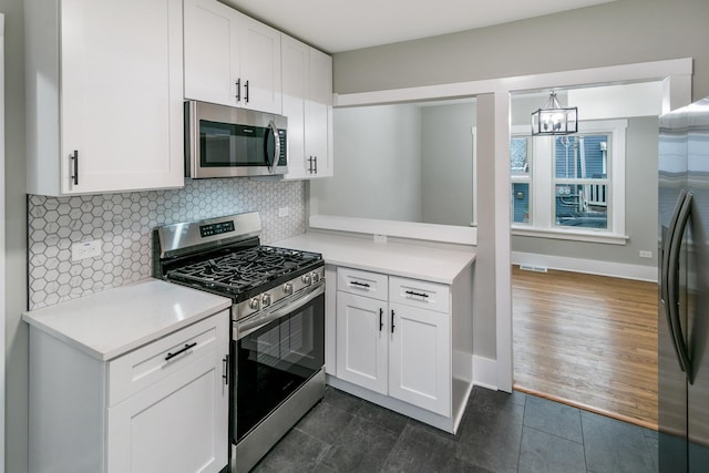 kitchen with backsplash, white cabinets, appliances with stainless steel finishes, decorative light fixtures, and a chandelier