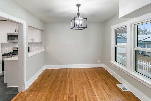 unfurnished dining area with light hardwood / wood-style floors and an inviting chandelier