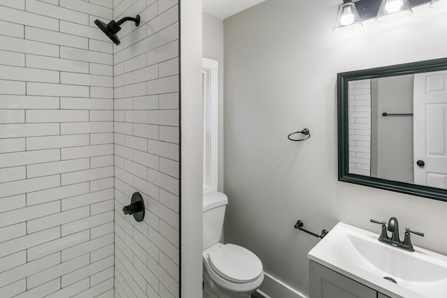 bathroom featuring vanity, toilet, and a tile shower