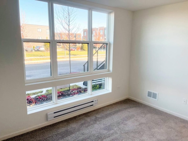 empty room featuring carpet, a healthy amount of sunlight, and a baseboard heating unit