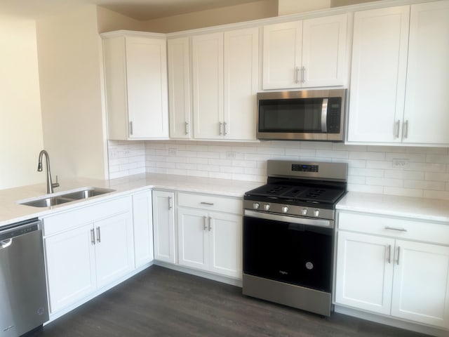 kitchen featuring dark hardwood / wood-style flooring, tasteful backsplash, stainless steel appliances, sink, and white cabinets