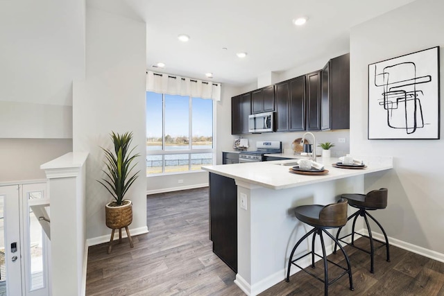 kitchen featuring a kitchen breakfast bar, dark hardwood / wood-style flooring, sink, and stainless steel appliances