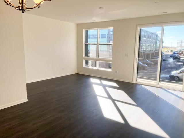 unfurnished room featuring a notable chandelier and dark hardwood / wood-style flooring