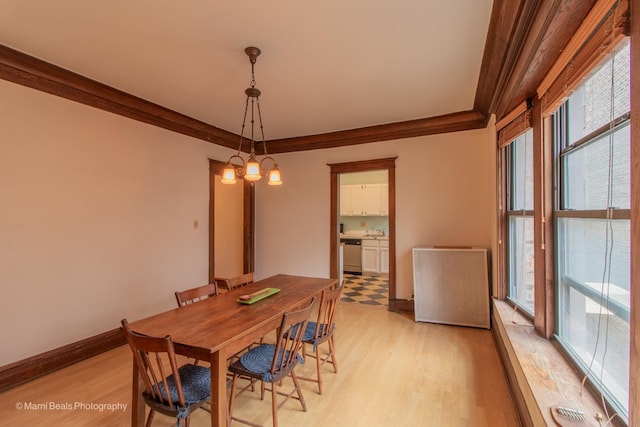 dining room with light wood-type flooring, crown molding, radiator, and a notable chandelier