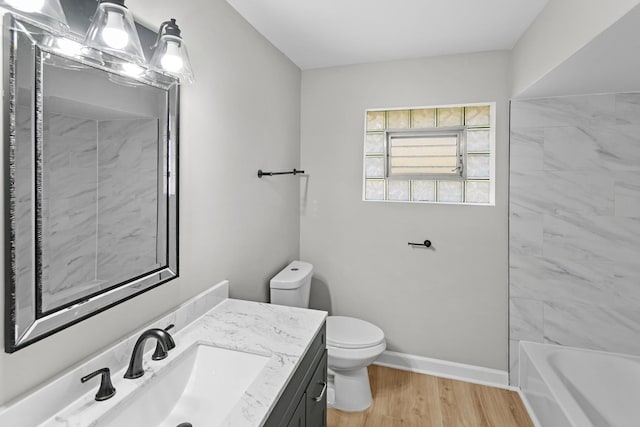 full bathroom featuring hardwood / wood-style floors, vanity, toilet, and tiled shower / bath