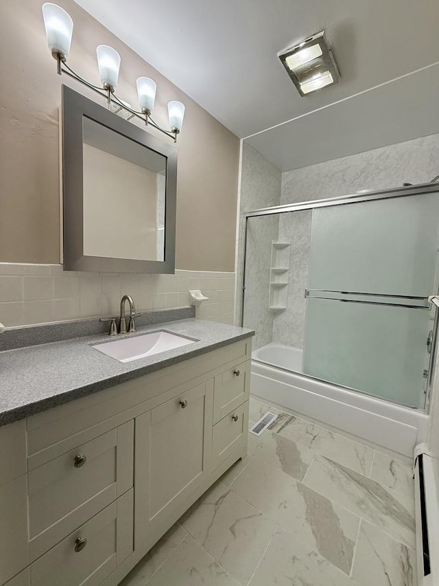 bathroom featuring baseboard heating, vanity, and combined bath / shower with glass door