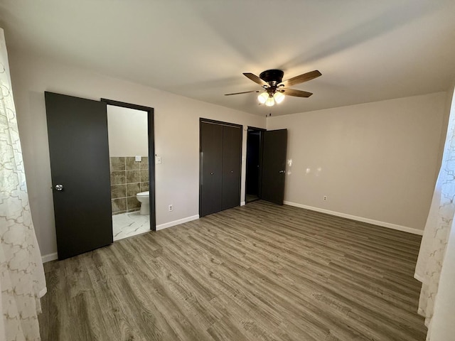 unfurnished bedroom featuring ensuite bath, ceiling fan, and hardwood / wood-style floors