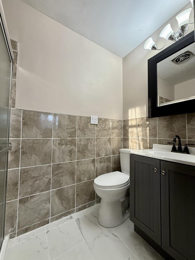 bathroom featuring vanity, toilet, and tile walls